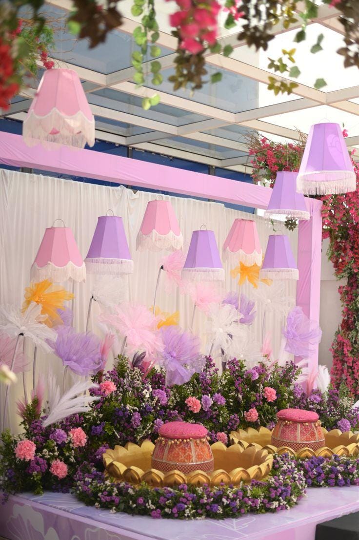 Pastel dessert table with lampshades, feathers and florals under a canopy by RAW Group